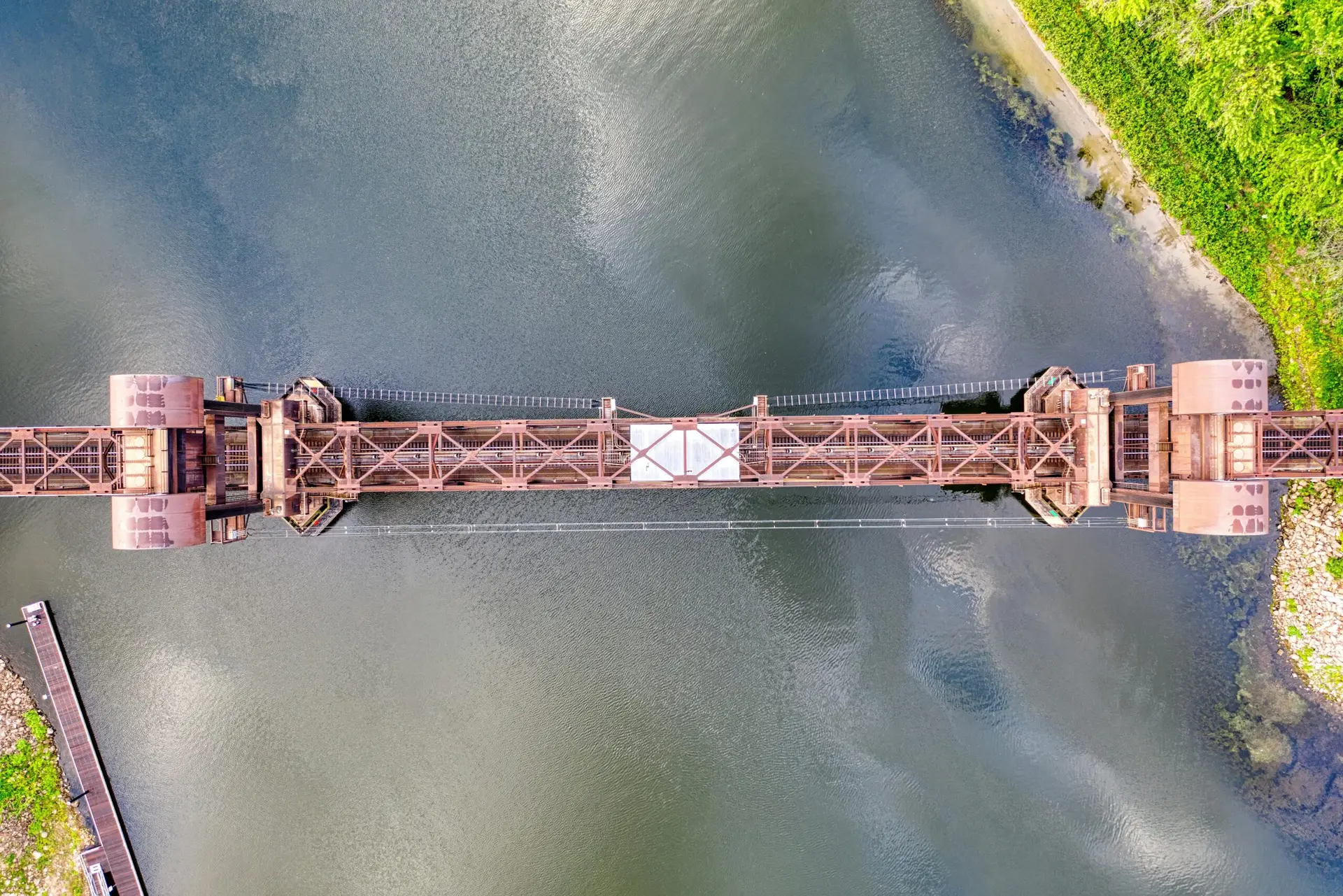 Drone shot of an iconic lift bridge over a tranquil river in Prescott, WI, showcasing industrial elegance.