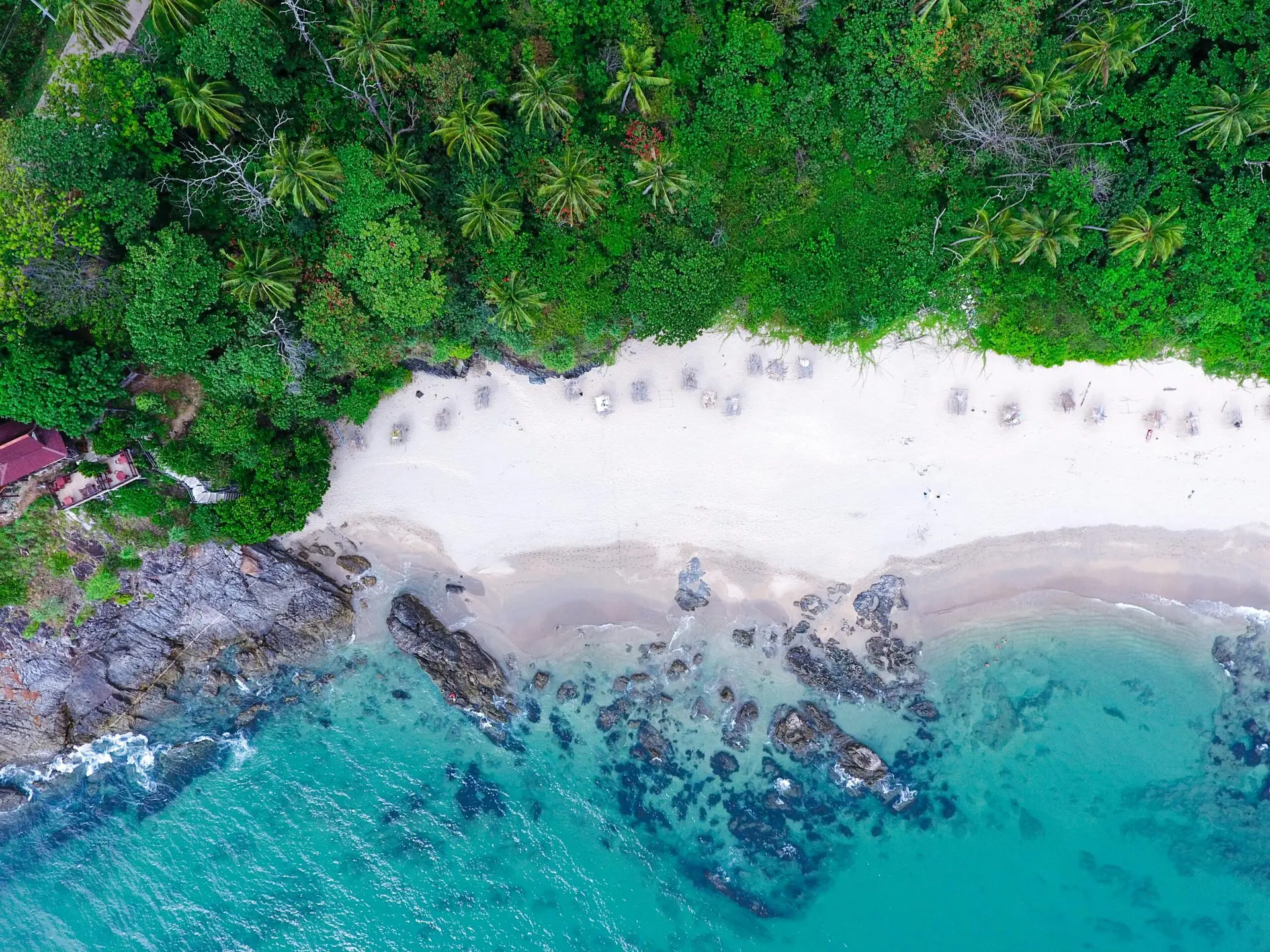 Stunning aerial view of a tropical beach with turquoise waters and lush greenery.