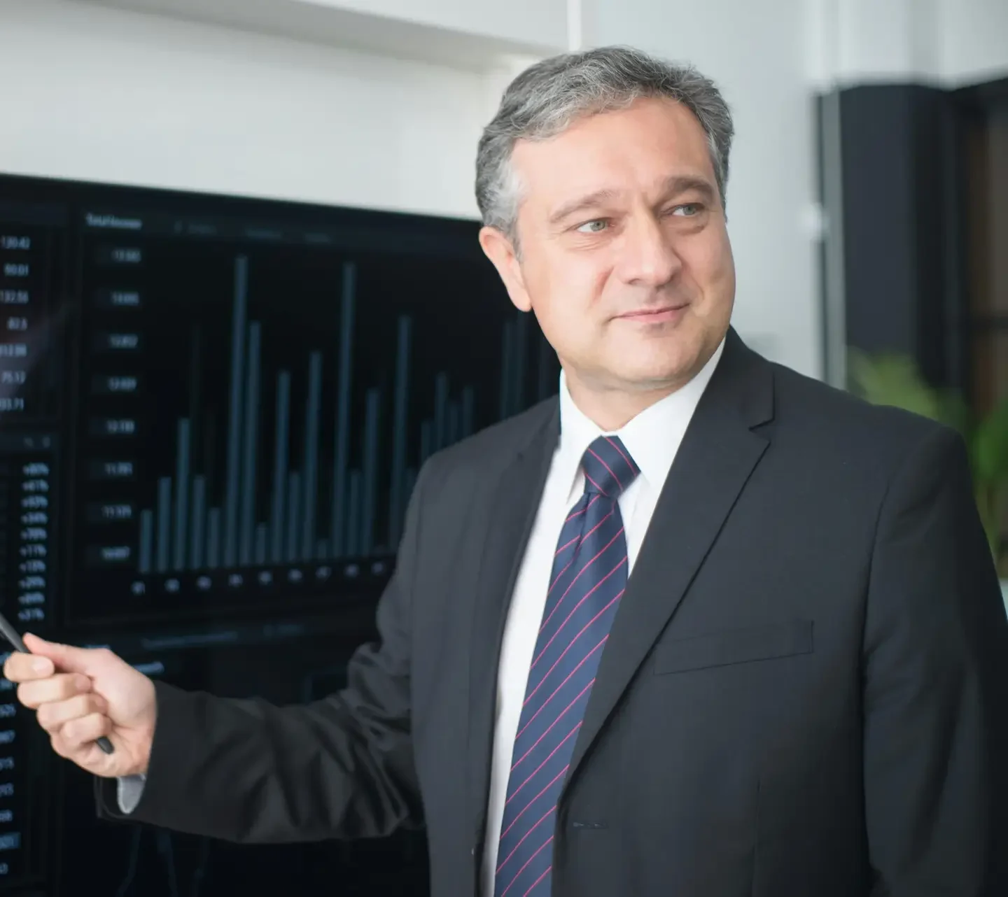 Professional man in suit reviewing financial charts on monitor, showcasing stock market trends.